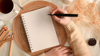 Female taking notes on notepad in minimal feminine workspace.