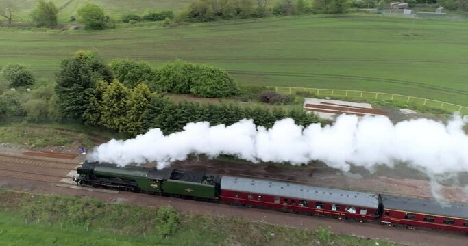 Right to left aerial tracking shot of the Flying Scotsman Steam train making it's way through the countryside on approach to the Forth Rail Bridge