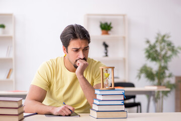 Young male student preparing for exams in time management concep