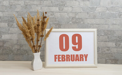 february 9. 9th day of month, calendar date.  White vase with ikebana and photo frame with numbers...