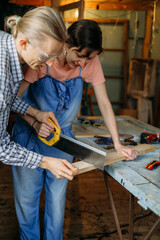Man teaching Woman to working with wood in workshop. Sewing wood. Reuse, reduce, recycle old things. Aware consumption and gender equality. Tools to repair, professional carpenter