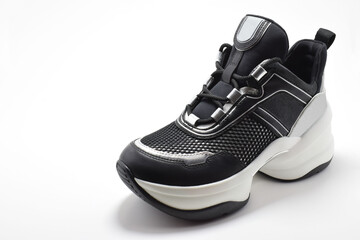 Zapato deportivo negro y gris sobre un fondo blanco. Calzado para hacer ejercicio, entrenar o caminar, espacio para texto al lado izquierdo.