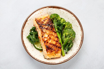 Baked salmon with vegetables on light background.