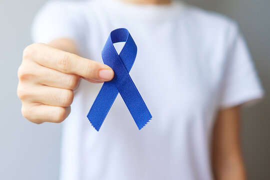 March Colorectal Cancer Awareness month, Woman holding dark Blue Ribbon for supporting people living and illness. Healthcare, hope and World cancer day concept