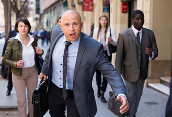 .Portrait of hurrying man among passers on street of city center