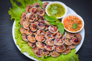Cockles with seafood sauce and vegetable salad lettuce on dark background, Fresh raw shellfish...