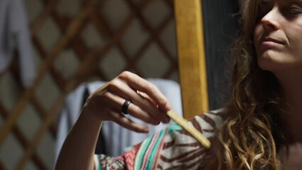 Beautiful woman in an ecovillage commune burns incense in a meditation ceremony