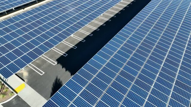 Aerial view from a drone shot above a solar carport with solar panels producing clean renewable energy from photovoltaic panels on a sunny day