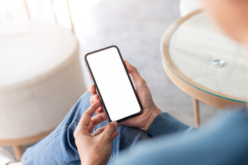 cell phone blank white screen mockup.hand holding texting using mobile on desk at office.background...