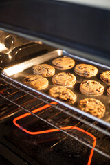 Chocolate chip cookies baking in oven on baking sheet