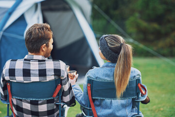 Young nice couple sitting on chairs inf front of tent on camping