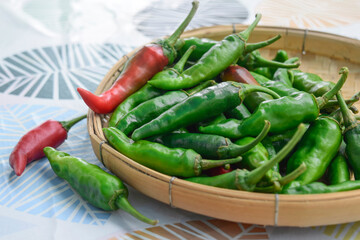 Close-up of fresh red and green peppers stacked on bamboo baskets.