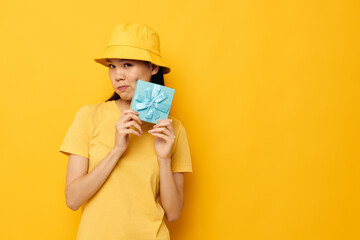 Portrait Asian beautiful young woman in a yellow T-shirt and a hat with a gift isolated background unaltered