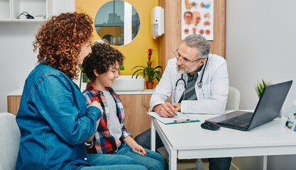 Friendly pediatrician communicate with her child patient at doctor's office while pediatrician...