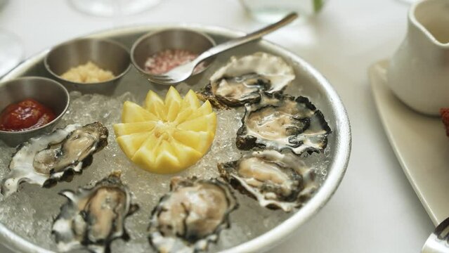 Fresh pacific oysters sitting on crushed ice with sauces slow motion 4k 30p
