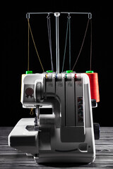 Professional overlock sewing machine with multicolored thread on a dark background
