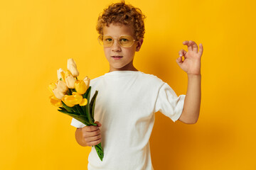 Photo portrait curly little boy with a bouquet of yellow flowers color background unaltered
