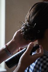 hairdresser's hands make a collected wedding hairstyle from which stilettos are visible