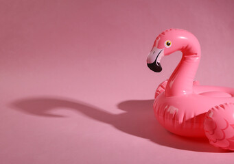 Pink inflatable flamingo with shadow on a pink background. Minimal summer layout