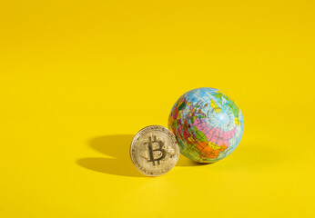 E-commerce. Gold bitcoin with globe on a yellow background with a shadow. Cryptocurrency. Minimal financial layout