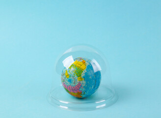 Globe under transparent dome on a blue background. Protection, isolation concept. Minimal layout
