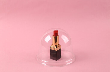 Showcase with lipstick under a transparent dome on pink background