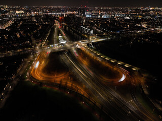 Fototapeta na wymiar Amsterdam at night, dutch infrastructure road intersection, train, road,track, metro and pedestrians. Aerial drone view.