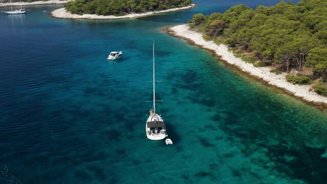 Sailboat Cruising Through Pristine Blue Waters Near Paklinski Islands In Croatia - aerial shot