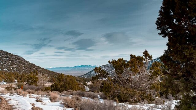 View of a high desert valley and the rocky mountains beyond as seen from a canyon in winter - time lapse