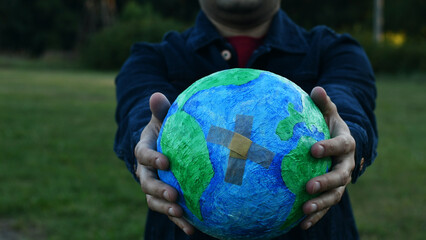 a man holds a globe with a sticking plaster.