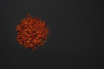 Dried rich scarlet red threads stigmas of organic persian saffron sargol spice on black background....