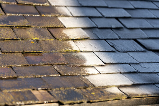 Frost melting on old roof tiles as sun breaks through in the morning melting ice causing a thaw. Low temperature frost in shade not melted yet.