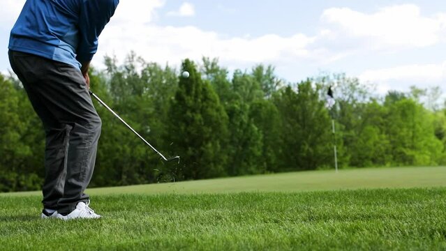 Male golfer hits a chip shot onto the green at a golf course