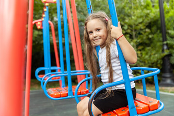 Fototapeta na wymiar Little cute girl riding a swing outdoors