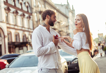 Cheerful loving couple in the city. A man gives his beloved woman a heart. Declaration of love