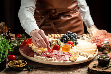 Traditional italian antipasto. Assorted cheeses, grapes, olives, prosciutto, rosemary. Delicious appetiser Italian prosciutto and Spanish Iberian ham snack