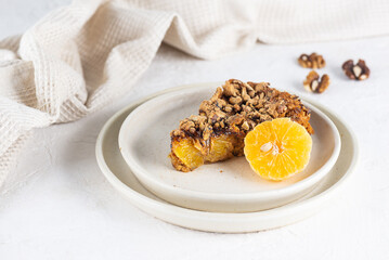 A piece of tangerine pie with walnuts in a plate on a white table. Sugar, gluten and lactose free, vegan.