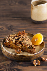 A piece of homemade pie with tangerines and walnuts on a wooden table. Sugar, gluten and lactose free, vegan.