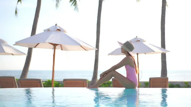 Classy exotic woman in pink swimsuit enjoying by swimming pool on hot sunny summer day, full frame