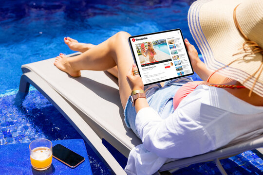 Woman watching online videos on tablet while relaxing by the pool
