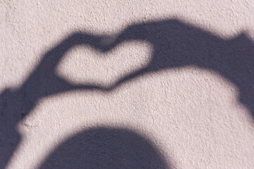 The shadow of a woman on the wall, which shows a heart with her hands. Symbol of love
