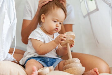 Mom and little daughter are playing with pyramid while sitting in wigwam at home © splitov27