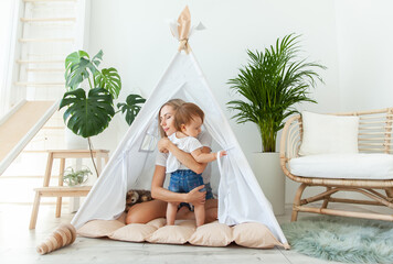Happy woman mom and her little daughter playing in wigwam at home © splitov27