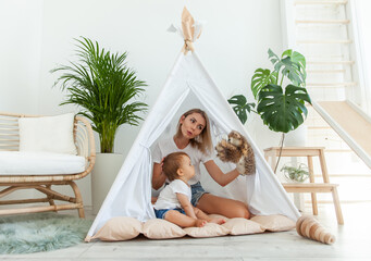 Happy woman mom and her little daughter playing in wigwam at home © splitov27