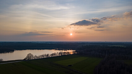 Fototapeta premium Aerial view shot by a drone of a beautiful dramatic and colorful sunset at coast of the lake. Nature landscape. Nature in Europe. reflection, blue sky and yellow sunlight. landscape during sunrise or