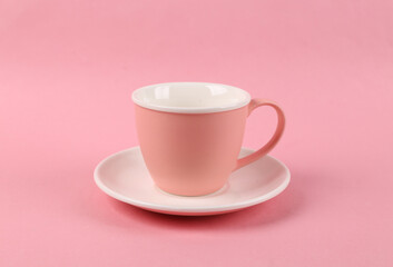 Empty ceramic cup and saucer on pink background
