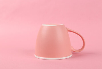 Inverted ceramic cup on pink background