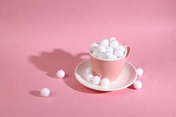 Ceramic cup with white balls on a pink background. Minimalistic still life