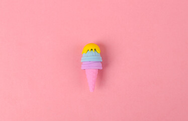 Plastic model of ice cream in cone on pink background. Minimal food flat lay