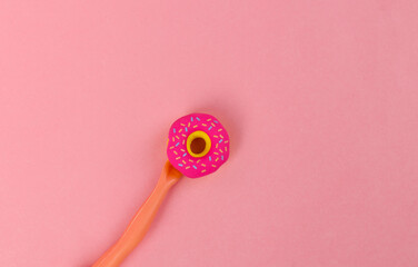 The doll's hand holding donut on pink background. Minimal concept. Creative layout